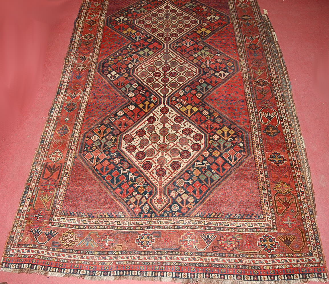 A late 19th century Persian woollen Luri rug, the rust coloured field decorated with three linked