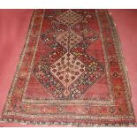 A late 19th century Persian woollen Luri rug, the rust coloured field decorated with three linked