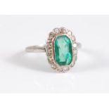 A platinum emerald and diamond ring, the rectangular octagonal step cut emerald, in rubover mount,