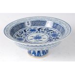 A Chinese porcelain blue and white stem bowl, decorated with flowers and foliage within Greek Key
