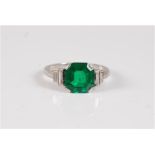 An emerald and diamond ring, the octagonal step cut emerald, approx. 8.5 x 8.1 x 4.2mm, in a four