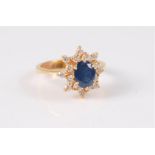 An 18ct sapphire and diamond cluster ring, the oval sapphire, claw mounted and surrounded by small