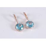 A pair of 14k topaz and diamond earrings, the round blue topaz, approx. 11mm diameter, surrounded by