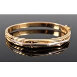 An 18k bi-colour gold and diamond hinged bangle, the upper half set with a three alternating band of