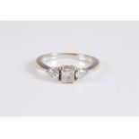 An 18ct three stone diamond ring, the central princess cut cut diamond set to either side with a