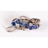 An early-mid 20th century blue and white sapphire brooch, set with two round white sapphires, collet