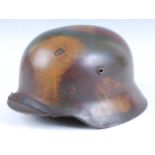 A German M1935 pattern steel helmet in camouflage finish, having a leather liner and chin strap,