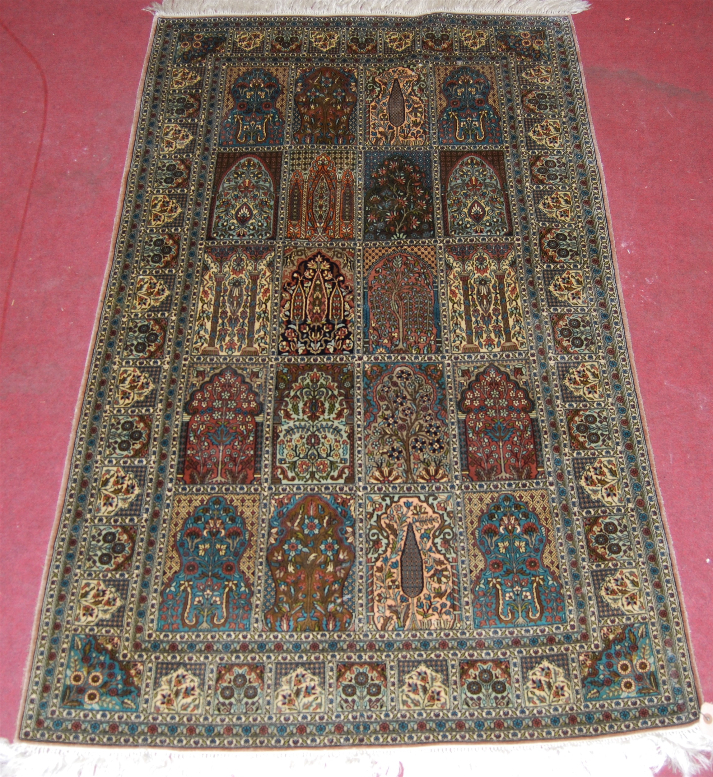 A Persian woven silk rug, having five rows of boxed reserves within multiple trailing tramline