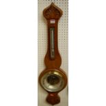 An early 20th century floral carved oak two dial aneroid wheel barometer