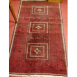 A Persian woollen rug, having a rust coloured field with three square medallions and multiple