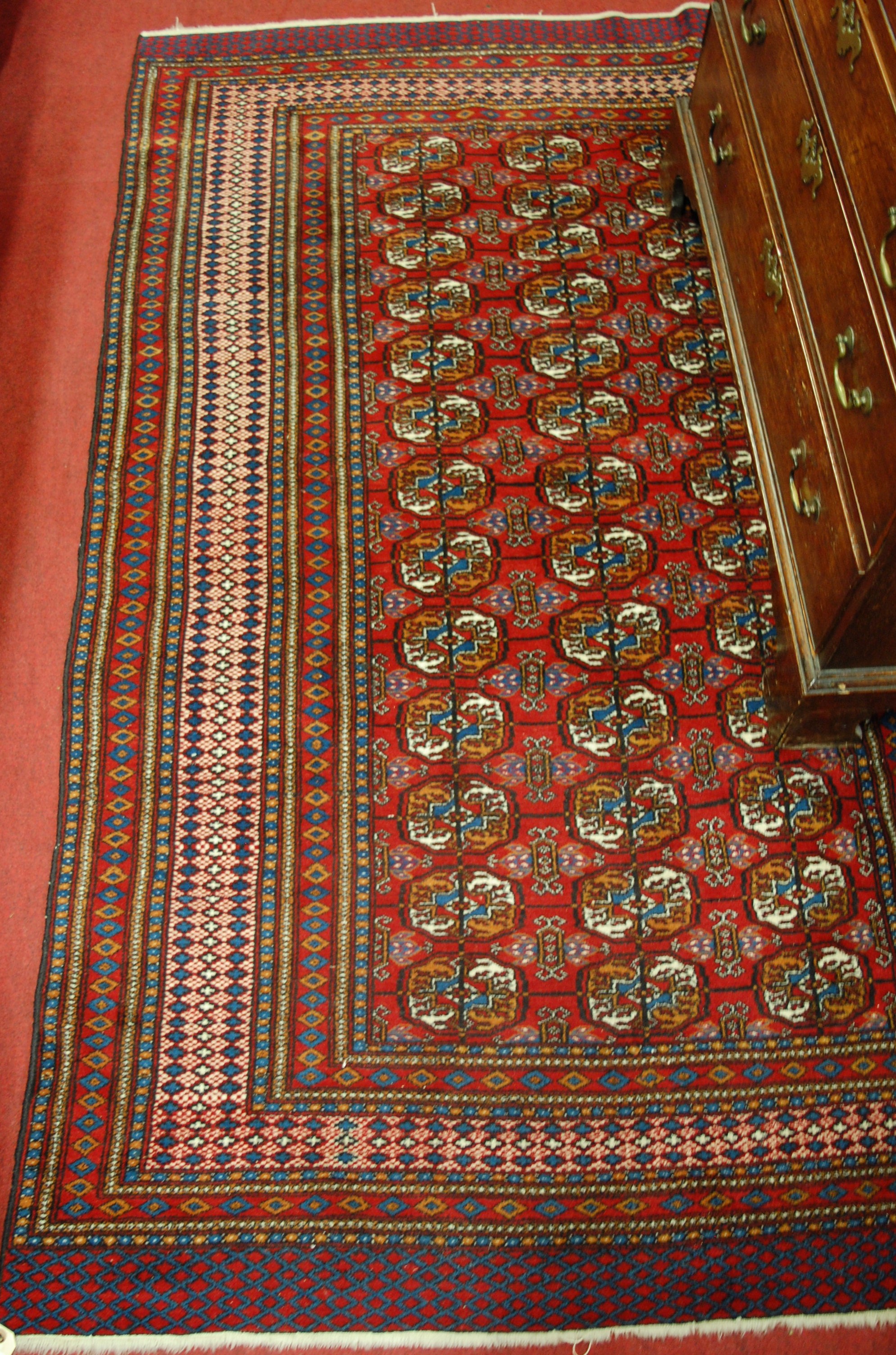 A Persian woollen red ground Bokhara rug, having multiple trailing borders, 200 x 130cm