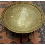 An engraved brass topped circular benares table, raised on relief carved folding base, dia. 68.5cm