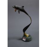 A contemporary bronze metal sculpture of a dolphin on a spirally turned support and marble base,