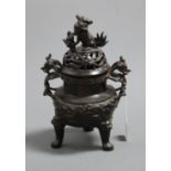 A bronze koro and cover, the pierced cover surmounted by a Dog of Fo, the base having grotesque twin