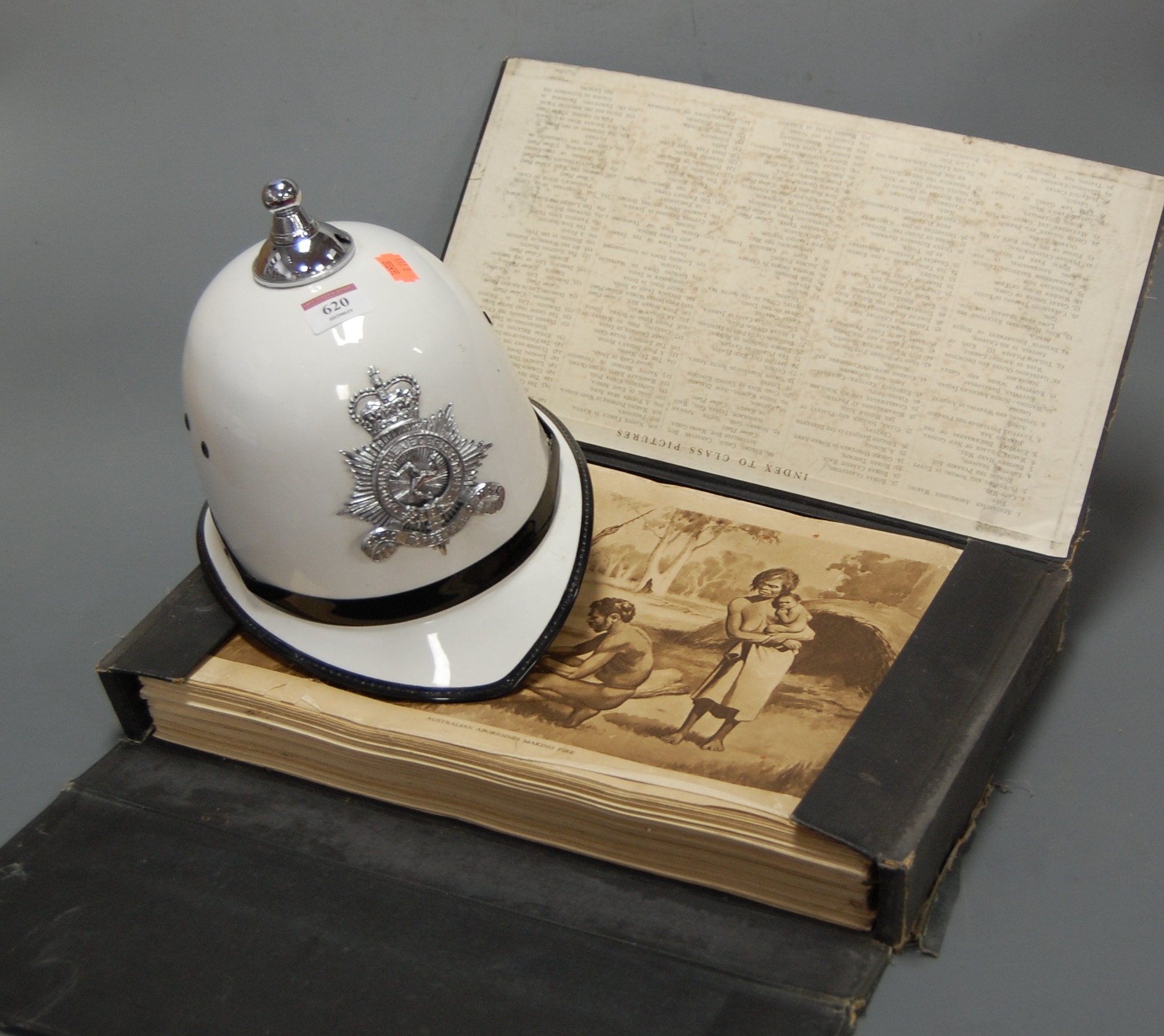 A reproduction police helmet; together with a folio of prints with index card to interior lid