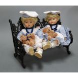 A Victorian style dolls cast iron bench; together with two modern dolls