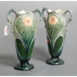 A pair of continental Art Nouveau pottery twin handled vases each relief decorated with flowers on a