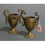 A pair of Victorian gilt brass twin handled urns, each having a ram's mask frieze with fluted