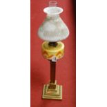 An early 20th century oil lamp, having shaped opalescent glass shade above a yellow and orange glass