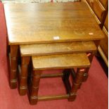 A contemporary oak nest of three occasional tables, raised on turned and square cut supports, the