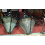 A pair of large black painted wrought iron hexagonal tapering wall mounted hanging street lights,