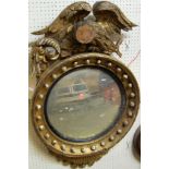 A Regency giltwood and gesso convex wall mirror, of good size, having eagle surmount (with