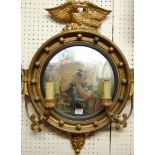 A Regency style gilt decorated circular convex wall mirror, having eagle surmount and twin candle