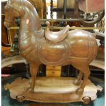 A Middle-Eastern stained and carved hardwood childs horse on wheels, having removable saddle, length