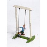 A Britains No. 619 boy on swing, comprising of white swing frame with brown seat with seated boy