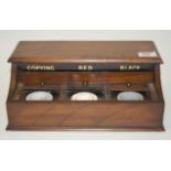 A walnut desk stand having hinge cover, and three annotated inkwells with sliding covers, width