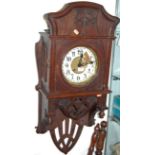 A continental art nouveau oak cased wall clock having an enamelled dial with Arabic numerals and 8-