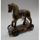 A 19th century carved and dapple-grey painted child's push-along horse, on pine base with iron