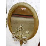 A 19th century French floral gilt decorated oval wall mirror, having candle branch arms (with