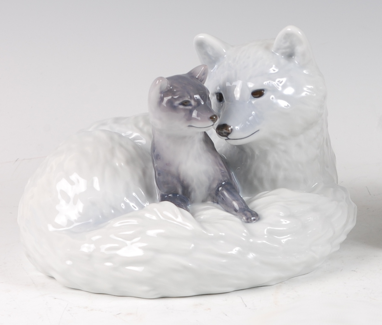 A Royal Copenhagen large porcelain model of an Arctic Fox with cub, in recumbent pose, printed