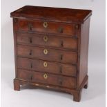 An antique walnut bachelors chest of small proportions, having a fold-over top with cross and