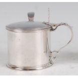 A George III silver mustard pot, of cylindrical form, having monogrammed hinged cover and blue glass