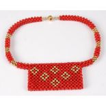 A beaded coral and yellow metal choker, the panelled front with yellow metal inset lozenge detail,