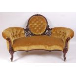 A Victorian rosewood framed settee, having a C-scroll acanthus leaf and flowerhead carved showframe,