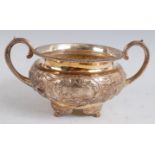 A George III silver twin handled sugar bowl, of squat circular form, having floral repousse
