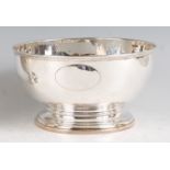 An Edwardian silver punch bowl, raised on stepped foot and with later vacant cartouche let into