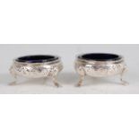 A pair of early George III silver table salts, with leaf and flower embossed decoration, raised on