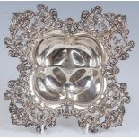 An early 20th century sterling silver dish, of quatraform, the pierced border relief decorated