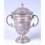 An Edwardian Indian Colonial white metal trophy cup and cover, the cover having chased and