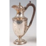 A George V silver hot water jug, the cover having acorn finial, ebonised handle with acanthus leaf