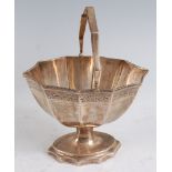 An Edwardian silver pedestal sweetmeat basket, having a swing handle with oval fluted body to a