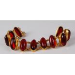 A yellow metal and cabochon *ruby glass* set bracelet, the eleven cabochons in open