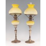 A pair of late Victorian silver candlesticks, each converted into oil lamps, with moulded yellow