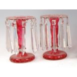 A pair of late 19th century Bohemian cranberry overlay pedestal table lustres, having cut flat