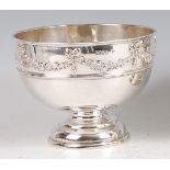 An Edwardian silver pedestal rose bowl, the broad rim chased with ribbons and floral swags to a