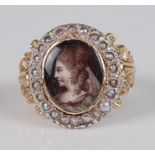 A George III yellow metal and seed pearl mourning ring, centre set with a monochrome painted profile